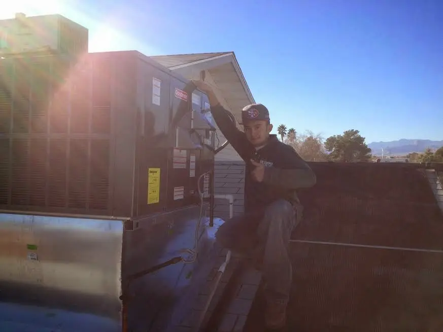 HVAC technician performing AC Tune-Up on a rooftop unit in Olean